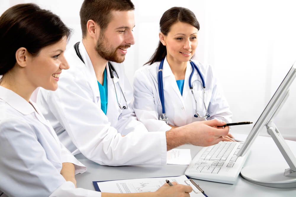 Doctors collaborating on patient data using a computer.